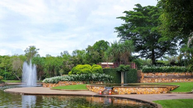 Ein angelegter Garten mit Brunnen, einem runden Teich und einer Steinmauer mit Sitzgelegenheit.