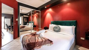 A modern bedroom with a large bed, a green headboard, and a mirror. - Urban Haven ~ Boutique 1BR Apt Near Parap Markets (Parap)
