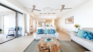 Ein modernes Wohnzimmer mit einem weißen Sofa, einem Couchtisch und einer Glastür, die auf einen Balkon führt.
