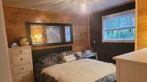 Un dormitorio con cama, cómoda, tocador y ventana con persianas.