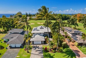 A residential area with houses, a golf course, and a view of the ocean.