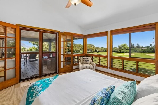A bedroom with a large bed, a chair, and a view of a golf course.