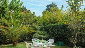 Un giardino con tavolo e sedie, circondato da diverse piante e alberi.