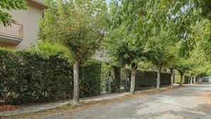 Una strada residenziale alberata con un edificio dotato di balcone.