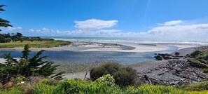 Un paysage côtier caractérisé par une plage de sable, des zones rocheuses et une végétation verdoyante.