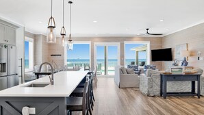 Una cocina moderna con una isla grande, un comedor y una sala de estar con vista al océano.