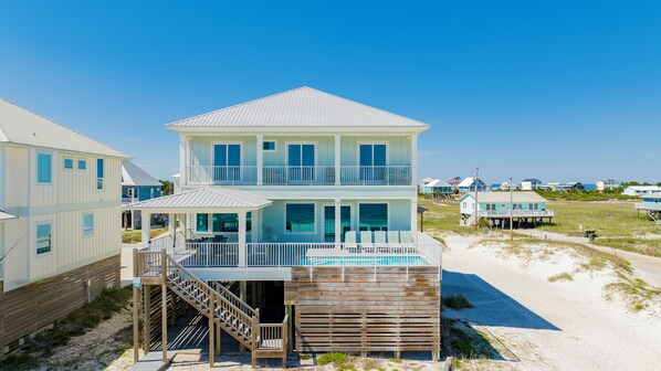 Una casa frente a la playa de dos pisos con balcón y piscina.