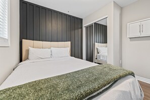 A bedroom with a bed, a wardrobe, and a mirror.