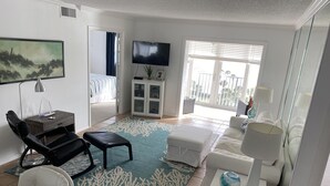 A living room with a TV, seating, a coffee table, and a view to the outside.