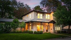 A two-story house with a stone facade, a covered porch, and a well-maintained lawn.