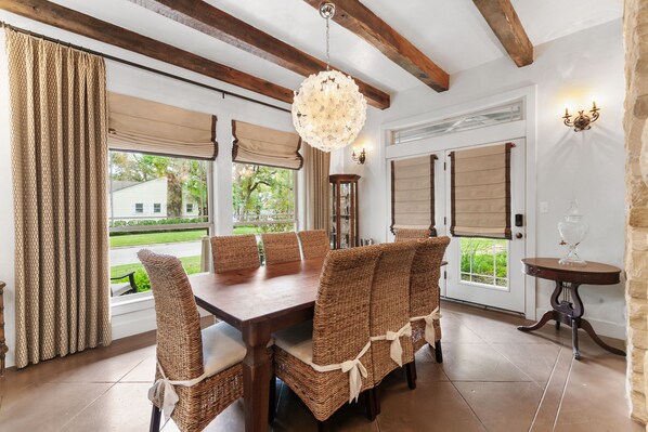 A dining area with a wooden table and wicker chairs, large windows with curtains, and a chandelier. - Central Austin Home w/ Pool/Spa / 5 mins Downtown  (Austin)