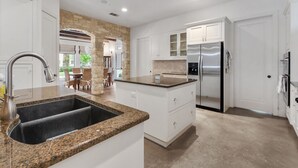 A modern kitchen with granite countertops, stainless steel appliances, and white cabinetry.