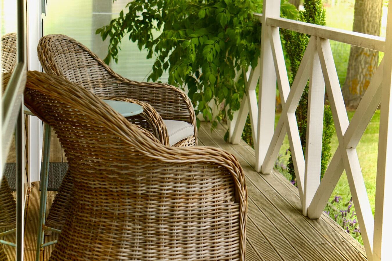 Wicker chairs on a wooden deck with a white railing.