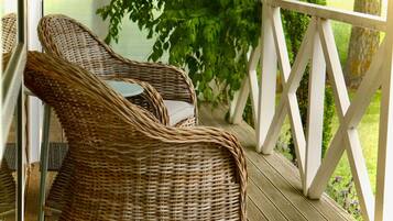 Wicker chairs on a wooden deck with a white railing.