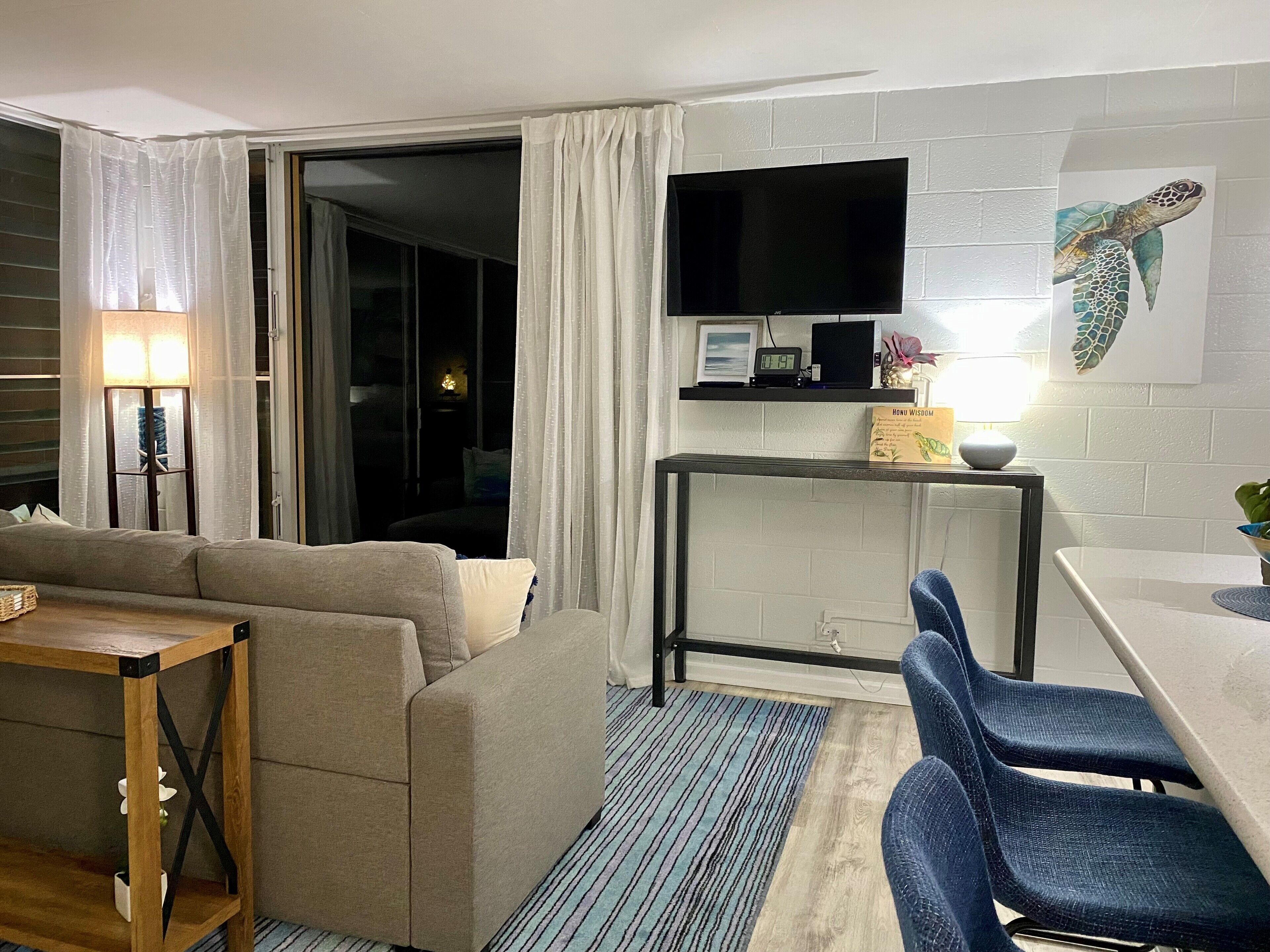 Una sala de estar moderna con un sofá, una mesa de comedor y un televisor montado en la pared.