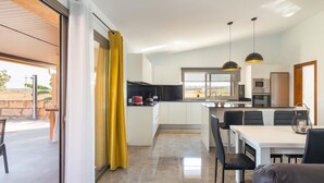 Una cocina moderna con comedor, ventanas amplias y vistas al exterior.