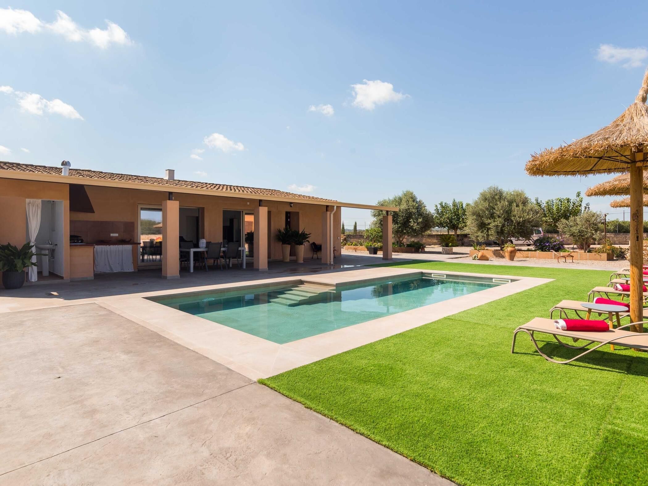 A modern house with a swimming pool, outdoor seating, and a well-maintained lawn.