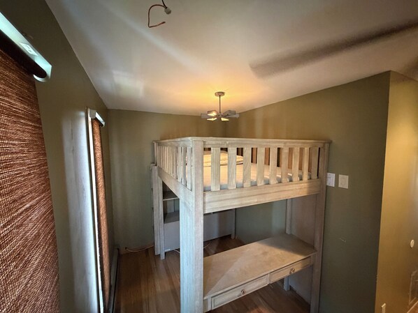 A bunk bed with a desk underneath, a ceiling fan, and a window with curtains. - Private Apartment Near UBS Arena &JFK (Elmont)