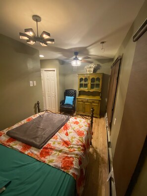 A bedroom with a bed, a chair, a cabinet, and a ceiling fan.