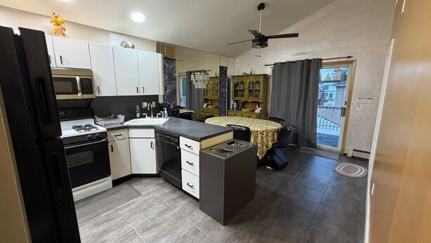 A modern kitchen with a gas stove, microwave, and white cabinets. - Private Apartment Near UBS Arena &JFK (Elmont)