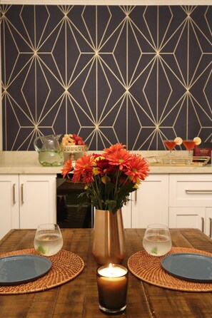 A dining table set with placemats, plates, a candle, and a vase of flowers.