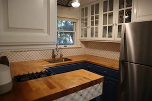 A kitchen with a wooden countertop, stainless steel appliances, and white cabinetry.