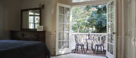 Une chambre avec un grand lit, une commode et une fenêtre donnant sur des arbres.