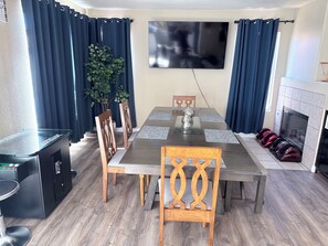A dining area with a table, chairs, a television, a fireplace, and a plant. - Charming Private Oasis- Approx 10 min to strip, Arcade Machine,FootMassagers (North Las Vegas)