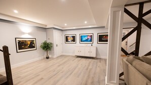 Una habitación amplia con piso de madera, un armario blanco con cajones y cuadros enmarcados en la pared.