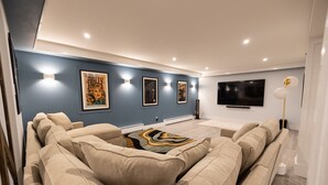 Una sala de estar moderna con un televisor grande, sofás color beige y obras de arte en las paredes.
