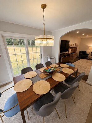 A dining area with a long wooden table, multiple chairs, and a chandelier.