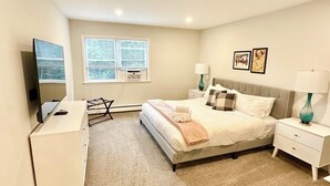 Un dormitorio con cama, mesitas de noche, escritorio, silla y televisor.