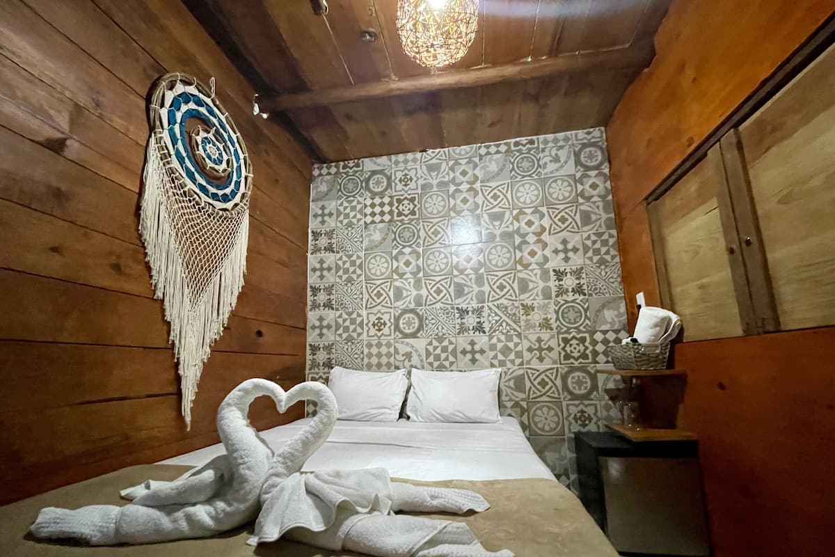 A wooden room with a bed, patterned tiles, and a decorative hanging.