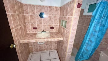 A small bathroom with a sink, a shower curtain, and a toilet.