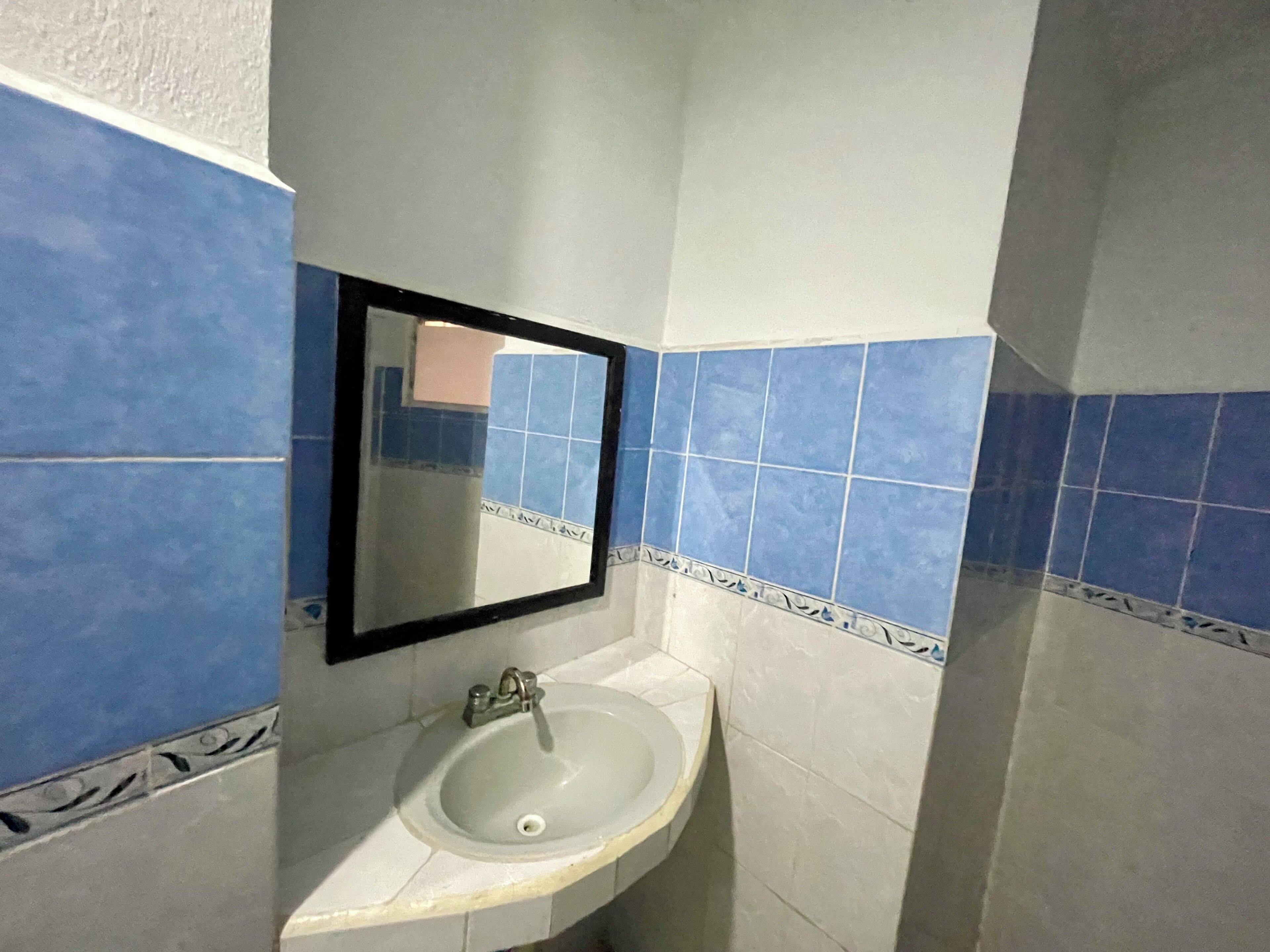A bathroom with a sink, mirror, and blue-tiled walls.