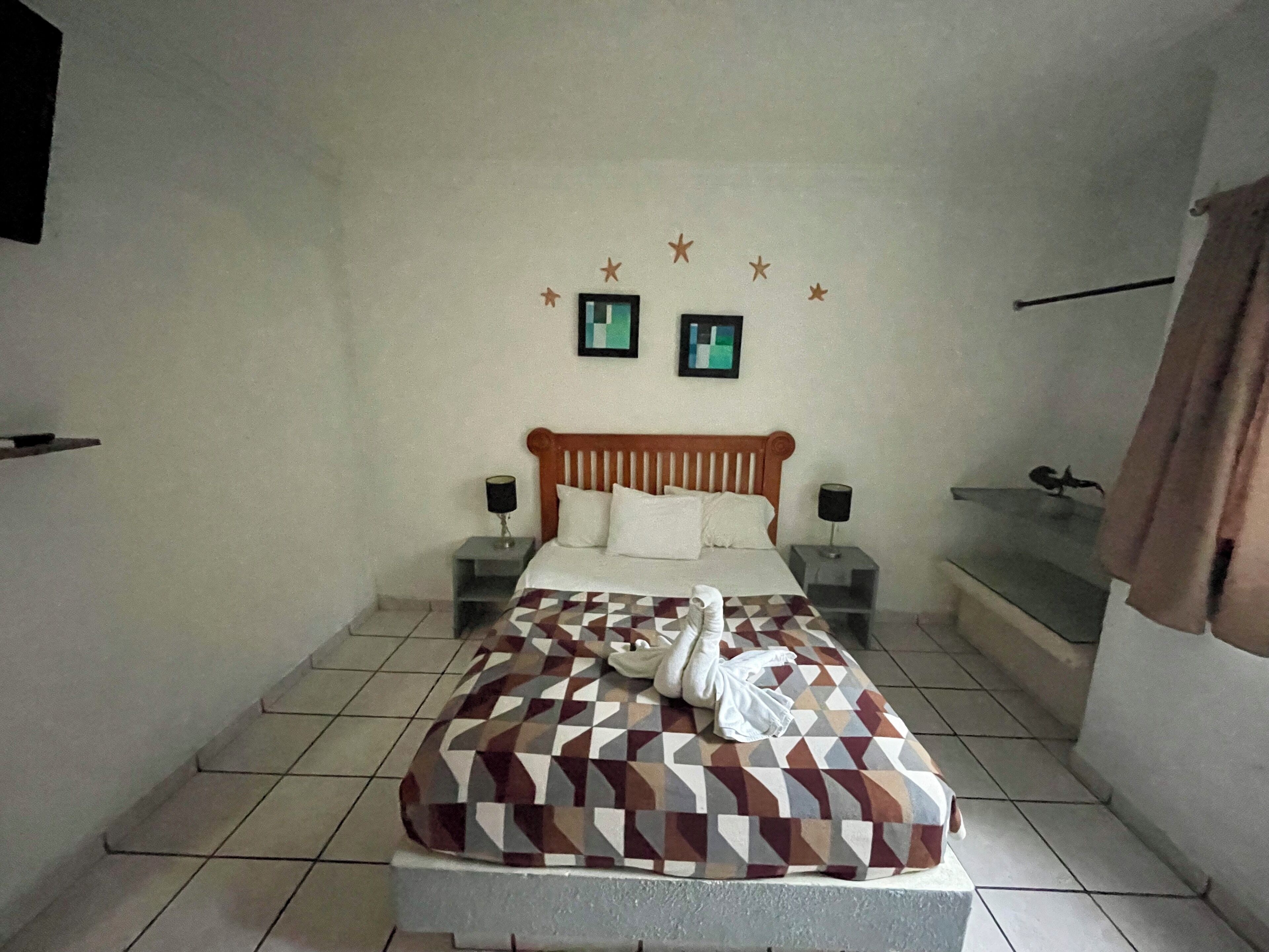 A bedroom with a bed, two bedside tables, a wall-mounted TV, and a star decoration.