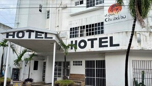 Un hotel con piso de baldosas a cuadros, una zona cubierta con un letrero y una palmera.