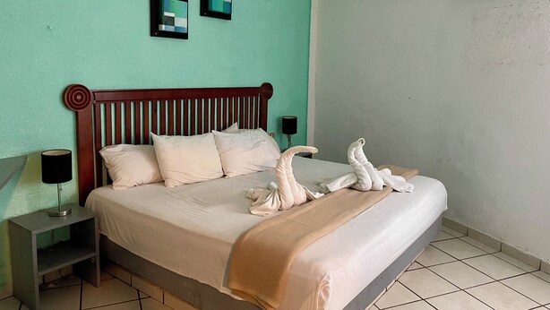 Una cama bien hecha con cabecera de madera, una lámpara de noche y un aire acondicionado instalado en la pared.