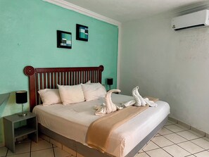 Un lit bien fait, avec une tête de lit en bois, une lampe de chevet et un climatiseur fixé au mur.