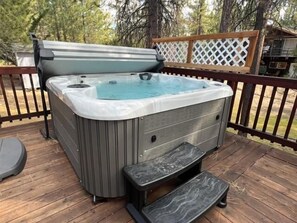 A hot tub on a wooden deck with a wooden railing and a lattice fence in the background. - Serenity Knoll - Hot Tub, Walk to Lake, Pool Table, Deck, Barbecue (Big Bear Lake)