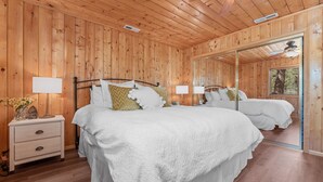 Un dormitorio con paneles de madera, una cama grande, mesitas de noche y un espejo.
