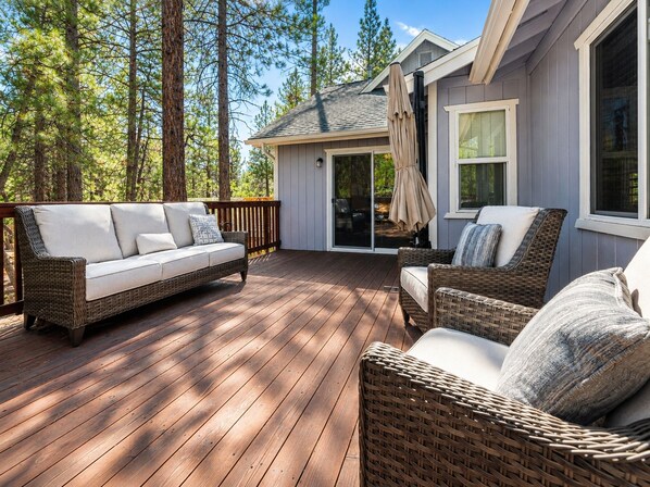 A deck with a sofa and chairs, surrounded by trees.