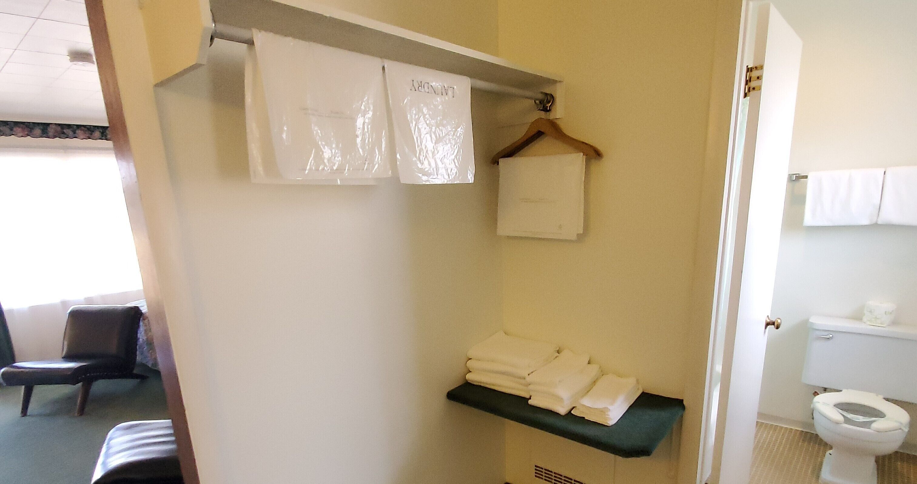 Un baño con inodoro, lavabo, toallero y una silla.