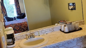 A bathroom with a sink, mirror, towel rack, and toiletries.