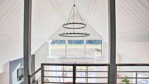 Una habitación amplia con techo alto, ventana grande y un candelabro moderno.