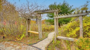Una estructura de pérgola de madera con un sendero de grava que atraviesa un jardín.