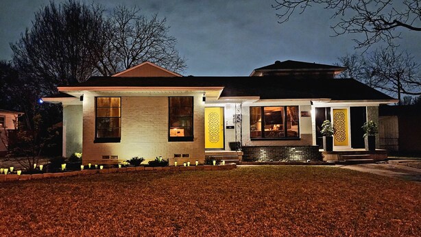 Una casa moderna con un ampio portico, un camino in pietra e un ingresso ben illuminato.