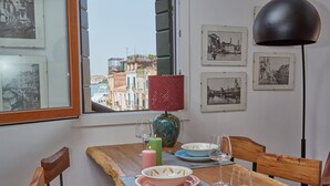 A dining table with plates, glasses, and candles, set against a window with a view of buildings. - Acqua Susanna - Penthouse with terrace (Venezia)