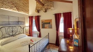 A bedroom with a brick ceiling, a metal bed frame, red curtains, a bedside lamp, and a framed picture on the wall. - Acqua Susanna - Penthouse with terrace (Venezia)
