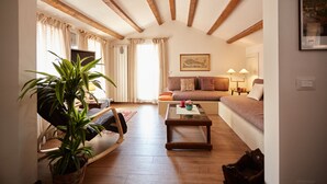 A cozy living room with a wooden ceiling, a sofa, a coffee table, and a potted plant. - Acqua Susanna - Penthouse with terrace (Venezia)